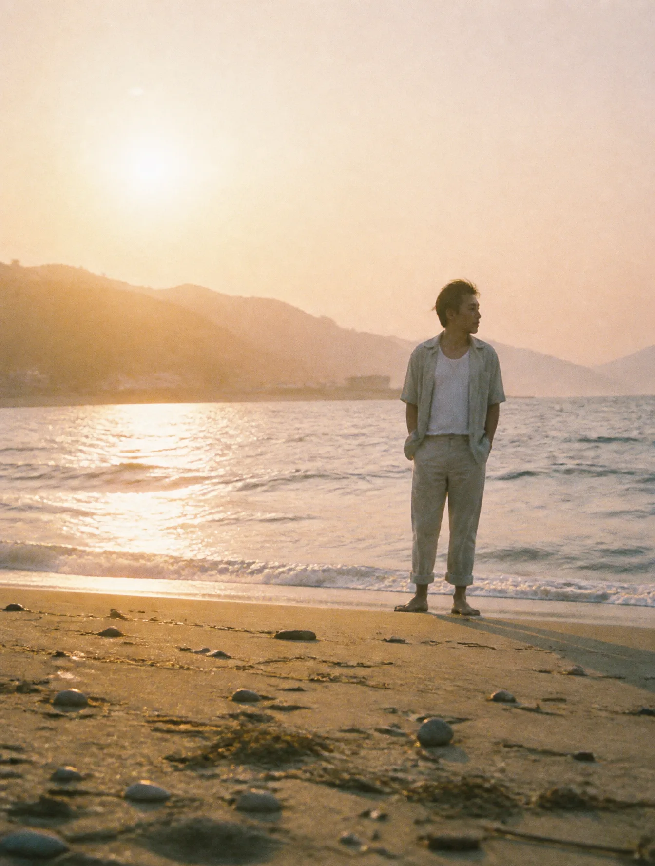A hazy beach scene at golden hour with a Japanese man in ...