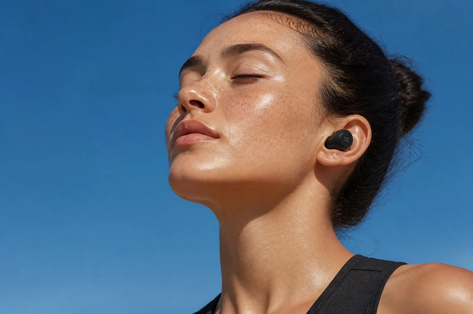 A serene close-up of a freckled woman with wireless earbu...