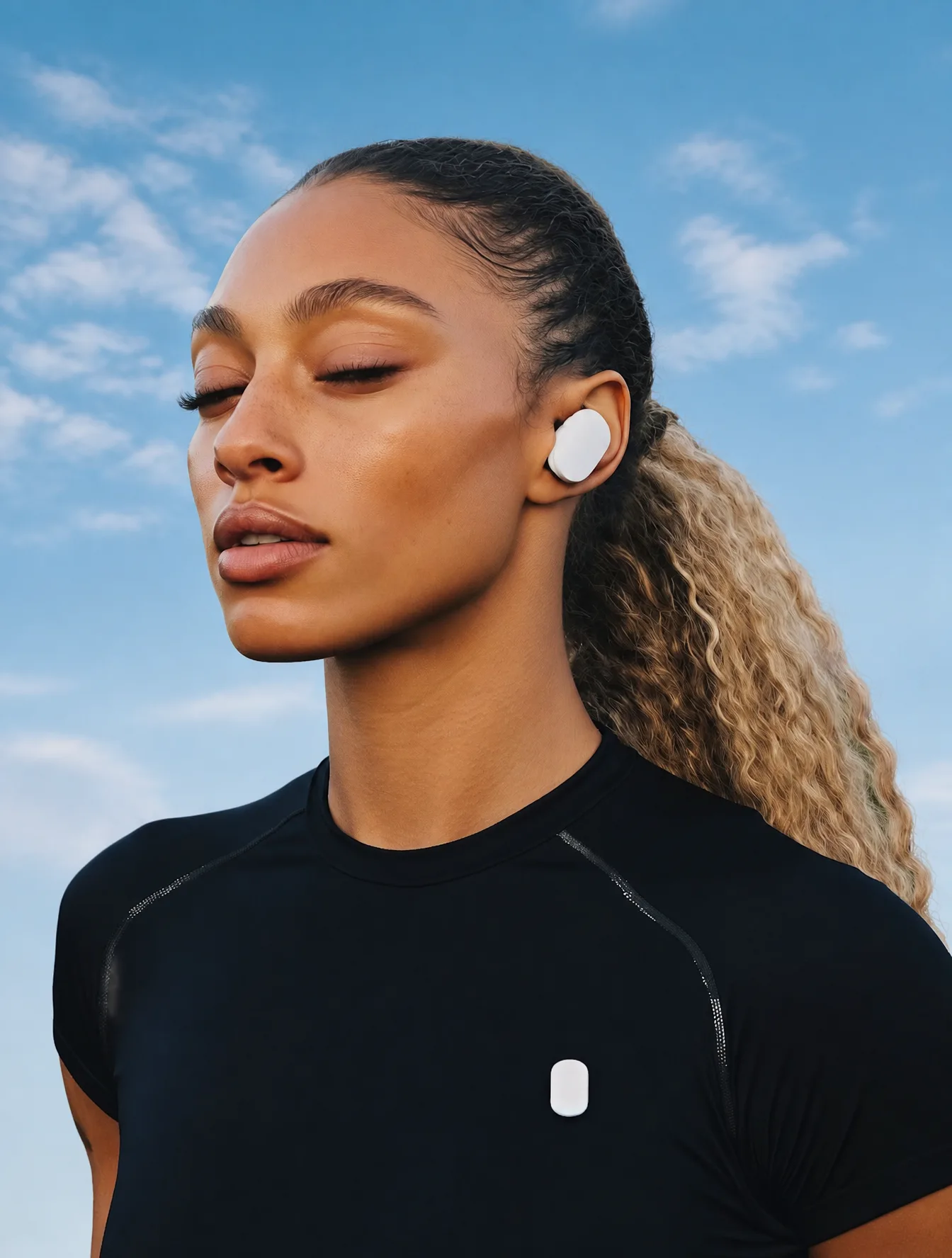 Confident woman with wireless earbuds in a blueish sky ba...