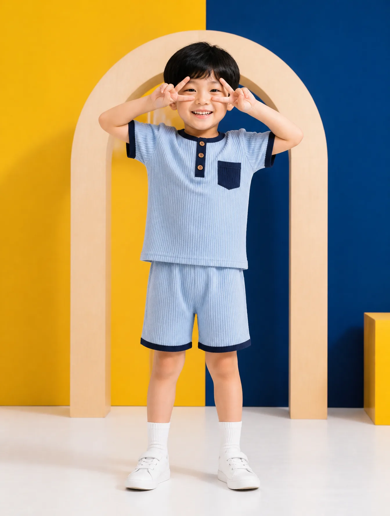 A young East Asian boy with a joyful expression stands ce...